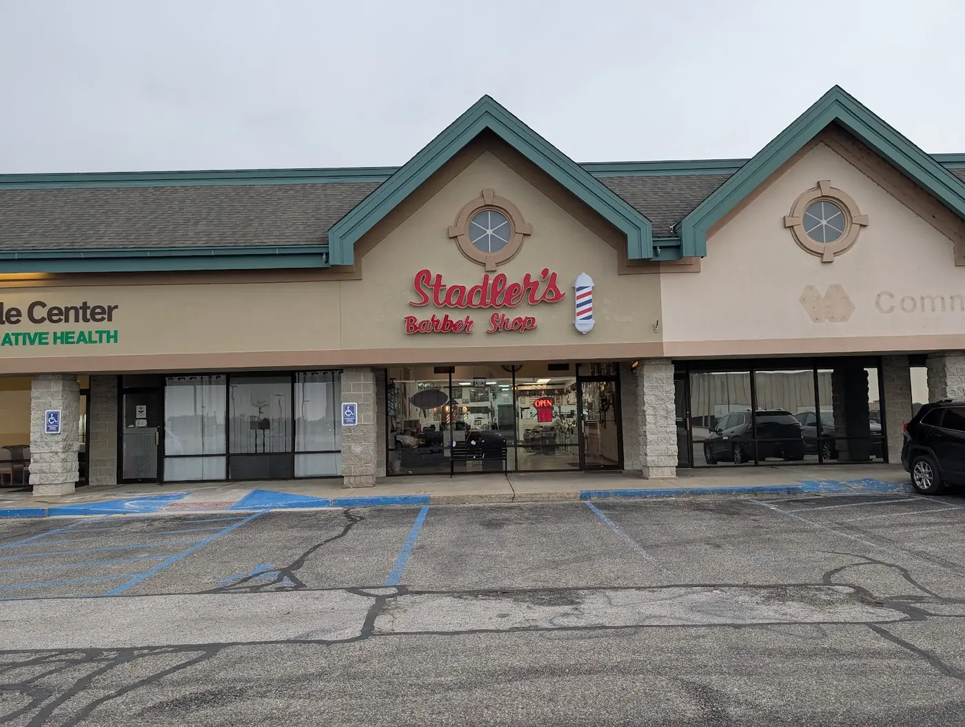 The Stadler's Barber Shop storefront: red script sign and barber pole under teal gables